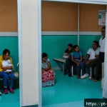 Home 18 베네수엘라 정치 망명 사례 - A crowded public hospital waiting room in a Latin American border city, filled with diverse Venezuel...